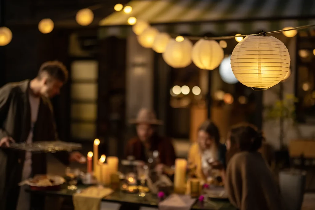 Soft lighting creates a cozy atmosphere as people enjoy food and conversation around a table